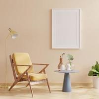 posterframemodel met verticale frames op lege crèmekleurige muur met gele fluwelen fauteuil. foto