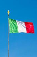 Italiaanse vlag van Italië zwaaiend in de blauwe lucht foto