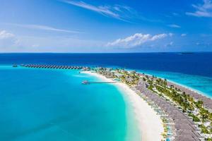 luchtfoto van het eiland maldiven, luxe watervilla's resort en houten pier. prachtige lucht en oceaan lagune strand. zomervakantie vakantie en reizen concept. paradijs luchtlandschap panorama foto