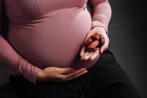 zwangere vrouw met dadelpalmfruit op zwarte achtergrond foto