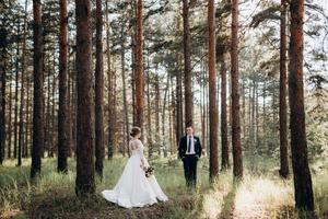 de bruid en bruidegom lopen in een dennenbos foto