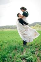 de bruidegom in een bruin pak en de bruid in een ivoorkleurige jurk op een groen veld foto