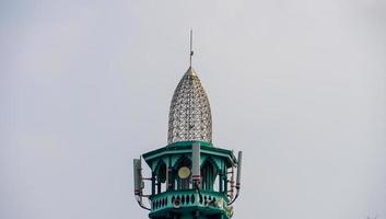 de top van een moskee-minaret met een soort Indonesische traditionele architectuur. de minaret heeft luidsprekers als luidsprekeroproep tot gebed. foto