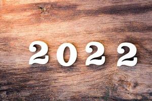 gelukkig nieuwjaar 2022 concept. houten tekst op bruin natuur houtstructuurpatroon.