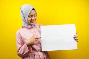 mooie jonge moslimvrouw vrolijk met lege lege banner, plakkaat, wit bord, leeg bord, wit reclamebord, iets presenteren in kopieerruimte, promotie foto