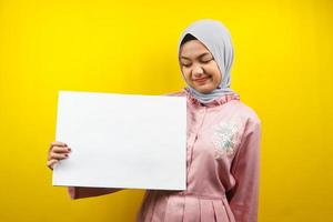 mooie jonge moslimvrouw vrolijk met lege lege banner, plakkaat, wit bord, leeg bord, wit reclamebord, iets presenteren in kopieerruimte, promotie foto