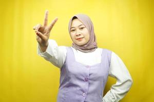 mooie jonge Aziatische moslimvrouw steenbolk met v-ondertekende handen, ok, goed gedaan, overeenkomst, overwinning, kijkend naar camera geïsoleerd op gele achtergrond foto