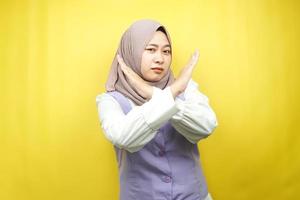 Mooie Aziatische jonge moslimvrouw met gekruiste armen, handen met weigering, handen met verbod, handen met afkeuring, geïsoleerd op gele achtergrond