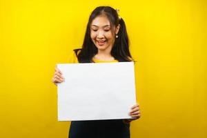 mooie en schattige jonge vrouw vrolijk met lege lege banner, plakkaat, wit bord, leeg bord, wit reclamebord, iets presenteren in kopieerruimte, promotie foto