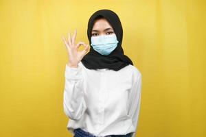 moslimvrouw die medische maskers draagt, anti-coronavirusbeweging, anti-covid-19-beweging, gezondheidsbeweging met maskers, met handen met ok teken, goed werk, succes, overwinning, geïsoleerd foto