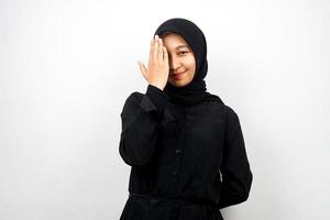 mooie aziatische jonge moslimvrouw die met hand één oog behandelt die camera bekijkt die op witte achtergrond wordt geïsoleerd foto