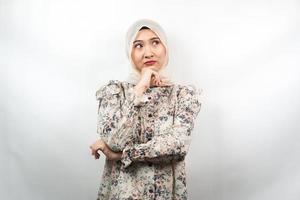 Mooie Aziatische jonge moslimvrouw denken, er is een probleem, zich vreemd voelen, er is iets mis, op zoek naar een oplossing, geïsoleerd op een witte achtergrond foto