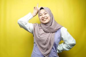 mooie jonge aziatische moslimvrouw die vol vertrouwen lacht, naar de camera kijkt geïsoleerd op gele achtergrond