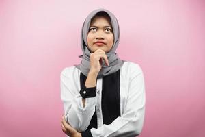 Mooie Aziatische jonge moslimvrouw denken, op zoek naar ideeën, op zoek naar oplossingen voor problemen, met handen met kin, geïsoleerd op roze achtergrond
