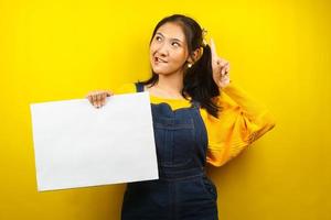 mooie en schattige jonge vrouw vrolijk met lege lege banner, plakkaat, wit bord, leeg bord, wit reclamebord, iets presenteren in kopieerruimte, promotie foto