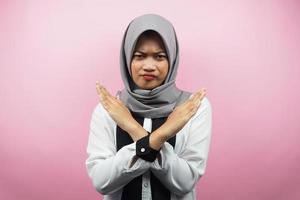 Mooie Aziatische jonge moslimvrouw met gekruiste armen, handen met weigering, handen met verbod, handen met afkeuring, geïsoleerd op roze achtergrond foto