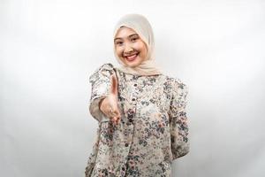 Mooie jonge Aziatische moslimvrouw glimlachend vol vertrouwen, met handen schudden van de camera, handen teken van samenwerking, hand teken van overeenkomst, hand teken van vriendschap, geïsoleerd op een witte achtergrond