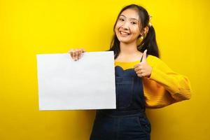 mooie en schattige jonge vrouw vrolijk met lege lege banner, plakkaat, wit bord, leeg bord, wit reclamebord, iets presenteren in kopieerruimte, promotie foto