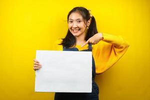 mooie en schattige jonge vrouw vrolijk met lege lege banner, plakkaat, wit bord, leeg bord, wit reclamebord, iets presenteren in kopieerruimte, promotie foto