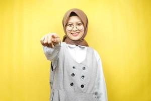 mooie jonge aziatische moslimvrouw met handen die naar de camera wijzen, je willen, naar je wijzen, bij je willen zijn, zelfverzekerd, enthousiast en vrolijk glimlachen, naar de camera kijken, geïsoleerd