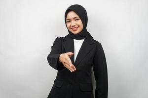 mooie jonge Aziatische moslim zakenvrouw zelfverzekerd en glimlachend, met handen schudden van de camera, handen teken van samenwerking, hand teken van overeenkomst, hand teken van vriendschap, geïsoleerd foto