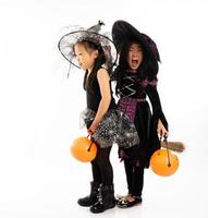 portret Aziatische meisjes in halloween-kostuum die samen op de bezem rijden en de pompoen vasthouden met geïsoleerde achtergrond