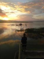 man visser vissen met een spinhengel in het meer in de middag. zonsondergang op limboto-meer, indonesië