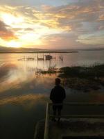 man visser vissen met een spinhengel in het meer in de middag. zonsondergang op limboto-meer, indonesië foto