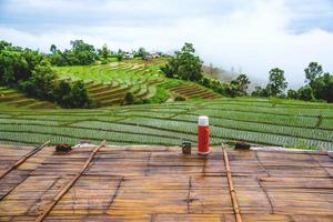 bidon en glas water lagen op het balkon van het resort. uitzicht op het rijstveldlandschap in het regenseizoen. bij papongpieng chiangmai in thailand. foto