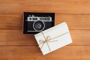 Kerstmis en Nieuwjaar vakantie geschenkdoos omwikkeld met wit papier en strik op houten tafel - bovenaanzicht op houten tafelblad achtergrond. foto