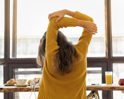 achteraanzicht van anonieme jonge vrouw met stijve spieren, gespannen en gewrichtspijn foto