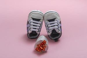 mockup van kinderschoenen. close-up van een geschenkdoos en gumshoes voor een pasgeboren baby op een gekleurde achtergrond. een cadeau aan vader foto