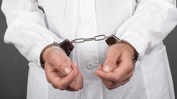 arresteer handen van een arts in handboeien close-up foto