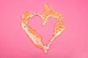 cannabis wax, verbrijzel dab marihuana extract gouden hartvorm op roze achtergrond foto