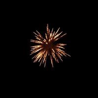 oranje vuurwerk barstte in de lucht en verlicht de lucht met oogverblindende vertoningen en kleurrijke vuurwerkfestivals op zwart. foto