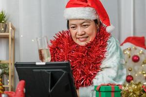 aziatische vrouw die champagne roostert viert nieuwjaar en kerstfeest videogesprek vrienden thuis foto