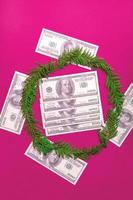 kerstkrans van dennentakken en gelddollars op een roze achtergrond. plat lag, bovenaanzicht, kopieer ruimte. feestelijke compositie