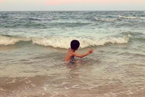 een jongen die in de zee speelt en alleen plezier heeft foto