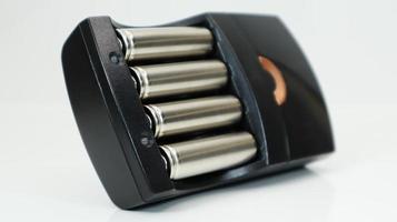 oplaadbare alkalinebatterijen in een batterijlader op een witte achtergrond. aa snellader in het zwart. de batterij wordt opgeladen. foto