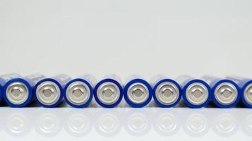 veel AA-alkalinebatterijen op een witte glanzende achtergrond met reflectie met kopieerruimte opgesteld in één regel. foto