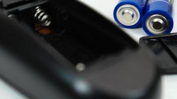 zwarte afstandsbediening met blauwe aaa-batterijen op een witte achtergrond. batterijvervanging, reserveonderdelen. batterij leeg compartiment van de close-up van de afstandsbediening. foto