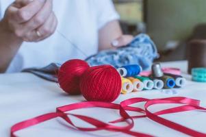 vrouwenhanden, een kleermaker naait kleren aan een tafel waarop klosjes draad liggen foto