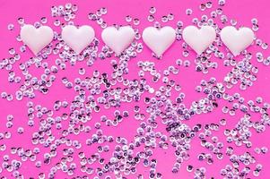 textuur. satijn roze hartjes en pailletten op een roze achtergrond. het uitzicht vanaf de top. het concept van relaties en liefde. foto