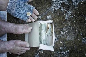 een munt in de handen van een dakloze man in handschoenen. armoede, werkloosheid, honger. foto