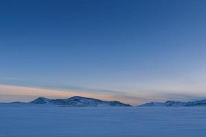 witte sneeuw bij het bouwen van prachtige zee wintersfeer met grote blauwe lucht in de heuvels van het luchtoppervlak. foto