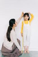 Aziatische moeder meet de lengte van haar dochter foto
