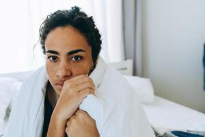 portret van een Afro-Amerikaanse vrouw wikkelde zichzelf in een deken en keek naar de camera foto