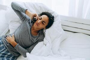 jonge zwarte vrouw die op mobiele telefoon praat terwijl ze in bed ligt foto