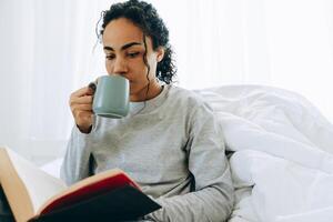 geconcentreerde Afrikaanse vrouw die koffie drinkt en een boek leest foto