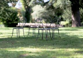vier metalen stoelen staan op gras voor mensen om te ontspannen in het bos.